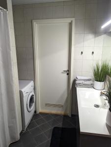 a bathroom with a washing machine and a white door at Studio Apartment with Sauna in Pärnu