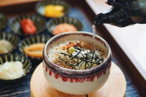 a person is pouring sauce into a bowl of food at Hotel Intergate Kanazawa in Kanazawa