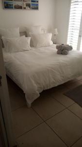 a large white bed with two stuffed animals on it at Unobstructed sea view gem (1 Spindrift) in St Francis Bay