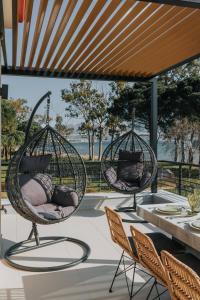 two hanging chairs on a patio with a table at Ponte Suites in Antirrio