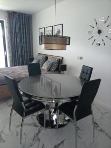 une salle à manger avec une table, des chaises et une horloge dans l'établissement Apartament Bieszczadzka A 8 Lesko, à Lesko