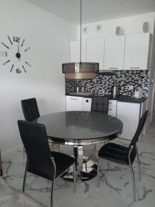 a dining room table with chairs and a clock on the wall at Apartament Bieszczadzka A 8 Lesko in Lesko