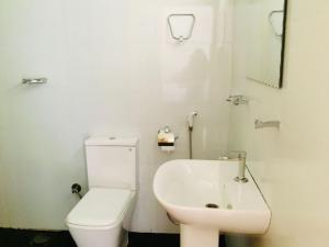 ein weißes Bad mit einem WC und einem Waschbecken in der Unterkunft Diyaluma Falls Inn in Koslanda