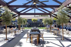 an outdoor patio with tables and chairs and trees at The Hadsten Solvang, Tapestry Collection by Hilton in Solvang
