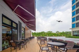 un patio extérieur avec des tables et des chaises et un avion dans l'établissement Hilton Garden Inn Guangzhou Airport Aerotropolis, à Huadu