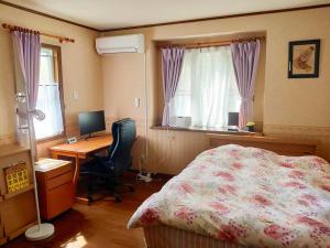 1 dormitorio con cama, escritorio y ordenador en Greenwood Cottage Nikko, en Nikko