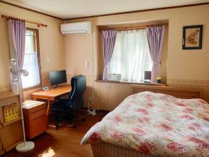una camera da letto con un letto, una scrivania e un computer di Greenwood Cottage Nikko a Nikko