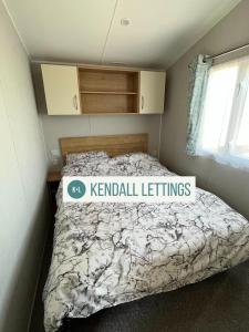 um quarto com uma cama com uma placa em Willerby (Green Lawns) em Selsey