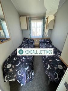 um pequeno quarto com duas camas e uma placa que lê mobiliário de canil em Willerby (Green Lawns) em Selsey
