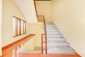 una escalera en una casa antigua con ventana en OYO Hotel Faizalia Tourist Home, en Perumpāvūr