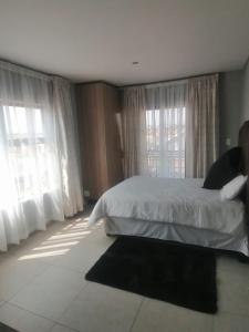 a bedroom with a bed and two large windows at Serenity Guest House in Soweto