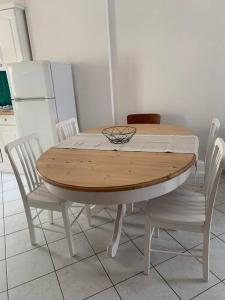 a wooden table with white chairs and a bowl on it at Agréable maison meublée in Cherbourg en Cotentin