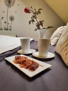 une assiette de nourriture sur une table avec deux tasses dans l'établissement Jaun-Ieviņas, à Rauna