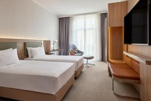 a hotel room with two beds and a flat screen tv at Courtyard by Marriott Schwerin in Schwerin