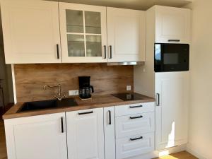 a kitchen with white cabinets and a sink and a refrigerator at Apartment Sonnenschwan - Neurenoviert, zentrumsnah und ruhig in Schliersee