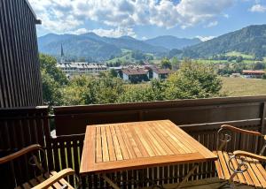 uma mesa de madeira numa varanda com vista para as montanhas em Apartment Sonnenschwan em Schliersee