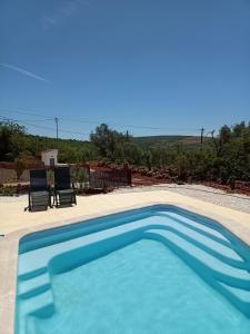 uma piscina azul com duas cadeiras num quintal em B&B Casa Flamenga em Alte