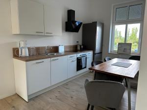 a kitchen with white cabinets and a wooden table and a table and chairs at Villa Schellhase in Werder