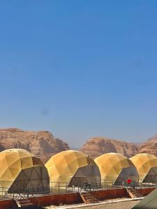 a row of domes in the desert with mountains at Sunrise Wadi Rum Camp in Wadi Rum