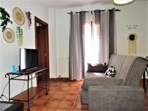 a living room with a couch and a television at APARTAMENTOS CASERIA DE COMARES in Granada