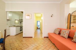 The Central House by Studio Vita في بولونيا: غرفة معيشة مع أريكة برتقالية ومطبخ
