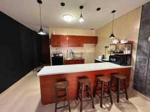 a kitchen with a bar with four stools at The Regency Seaview @PortDickson in Port Dickson