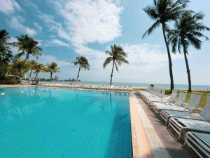 a swimming pool next to the beach with palm trees at The Regency Seaview @PortDickson in Port Dickson