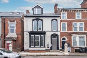 a white house with black windows and a car at Charnwood Flat 2 - 3BR Derby City Centre Flat in Derby