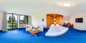 a hotel room with a large bed and blue carpet at Hotel Hohe Linde in Isny im Allgäu