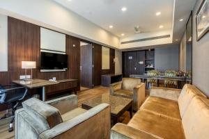 a hotel room with couches and a television and tables at GCC Hotel and Club in Mumbai