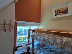 een slaapkamer met een stapelbed en een raam bij Family House Wakker in Eemnes