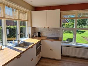 een keuken met witte kasten, een wastafel en ramen bij Family House Wakker in Eemnes