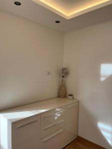 a white kitchen with a vase of flowers on a counter at Apartmani Ristanović in Zlatibor