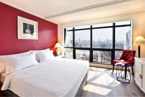 a bedroom with a large white bed and a red wall at Grand China Bangkok in Bangkok
