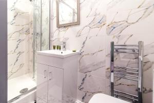 een witte badkamer met een wastafel en een toilet bij Charnwood Flat 4 - City Center 3BR Gem in Derby