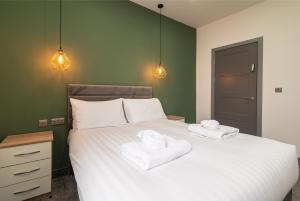 een slaapkamer met een wit bed en 2 handdoeken bij Charnwood Flat 4 - City Center 3BR Gem in Derby