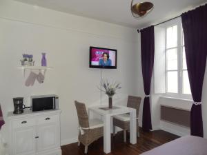 a room with a table with chairs and a tv at Studio Maison Fyot in Dijon
