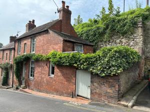 una casa de ladrillo con hiedra creciendo a un lado de ella en The Railway Cottage Bridgnorth en Bridgnorth