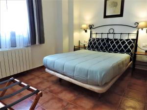 een slaapkamer met een bed, een stoel en een raam bij APARTAMENTOS CASERIA DE COMARES in Granada