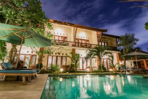 a villa with a swimming pool in front of a building at Mina Pelasa Hotel in Legian