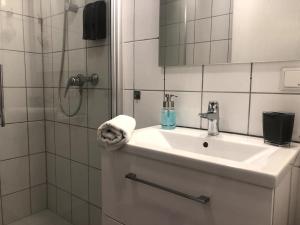 ein weißes Bad mit einem Waschbecken und einer Dusche in der Unterkunft Central Hub Kassel City in Kassel