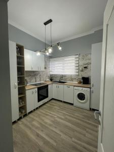 cocina con armarios blancos, lavadora y secadora en Casa Di David en Buzău