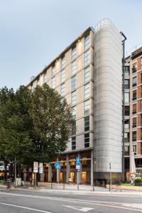 ein großes Gebäude in einer Stadtstraße mit einem Baum in der Unterkunft Tapestry by Hilton Ambasciatori Hotel in Mestre