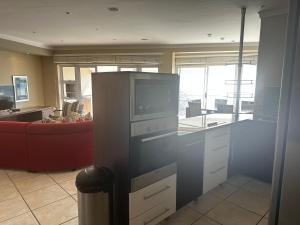 eine Küche mit einer Mikrowelle und einem roten Sofa in der Unterkunft Port Apartment with Sea Views in St Francis Bay