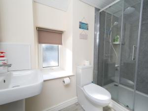 a bathroom with a shower and a toilet and a sink at Pass the Keys Spacious Cottage in central Benllech with parking in Benllech +25 photos