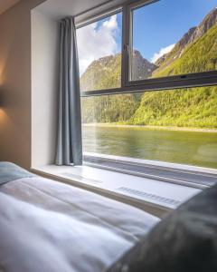 a bedroom with a window with a view of a lake at Fru Haugans Hotel in Mosjøen