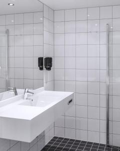 a white bathroom with a sink and a shower at Fru Haugans Hotel in Mosjøen