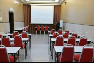 uma sala de aula com mesas e cadeiras vermelhas e um quadro branco em E-Suites Hotel, Abuja em Abuja