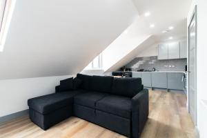 a living room with a black couch and a kitchen at Charnwood Flat 6 - Prime 3BR Derby City Centre Home in Derby