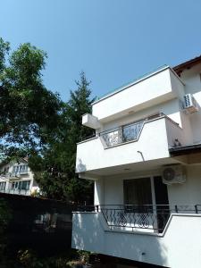 un edificio bianco con balcone e alberi di Цвят бяло a Sofia